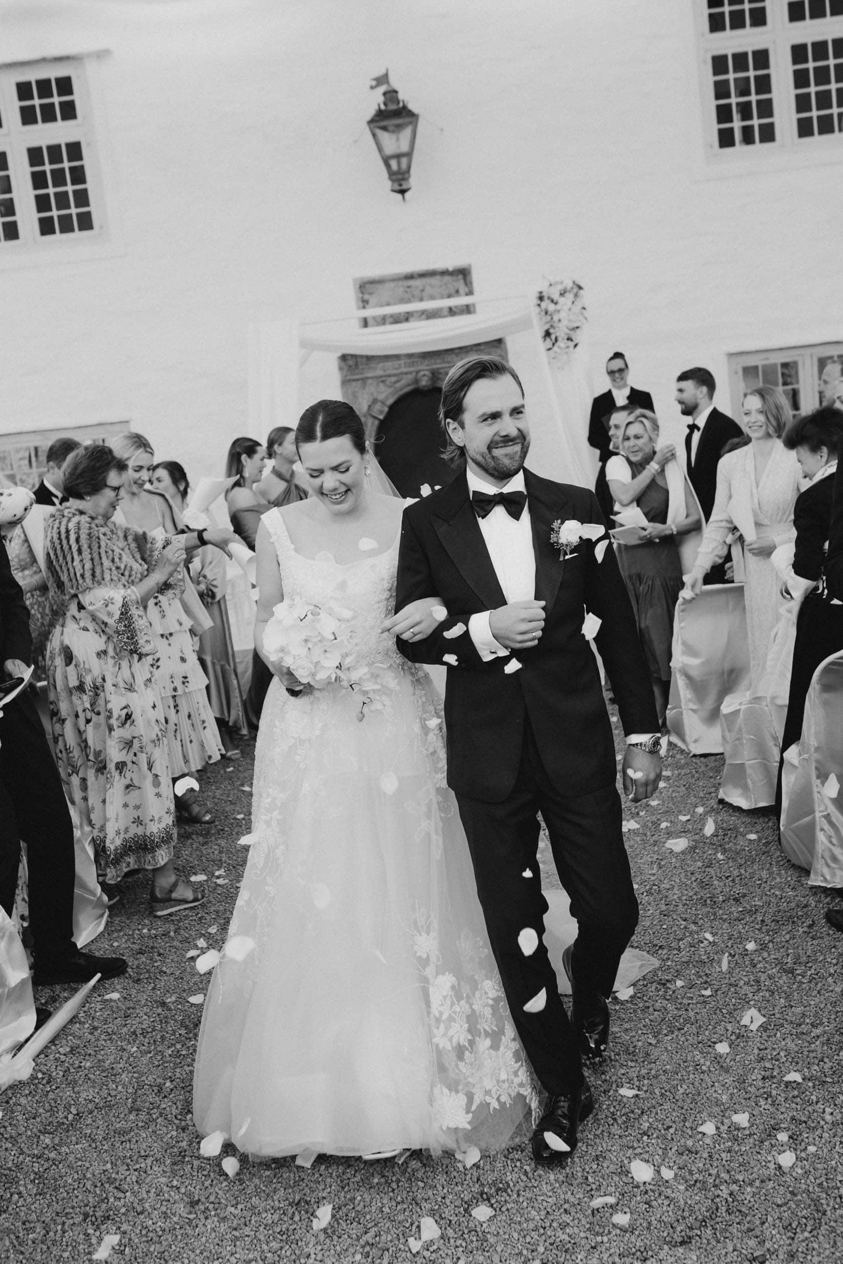 smilende brudepar og mennesker som kaster blomsterblad på dem