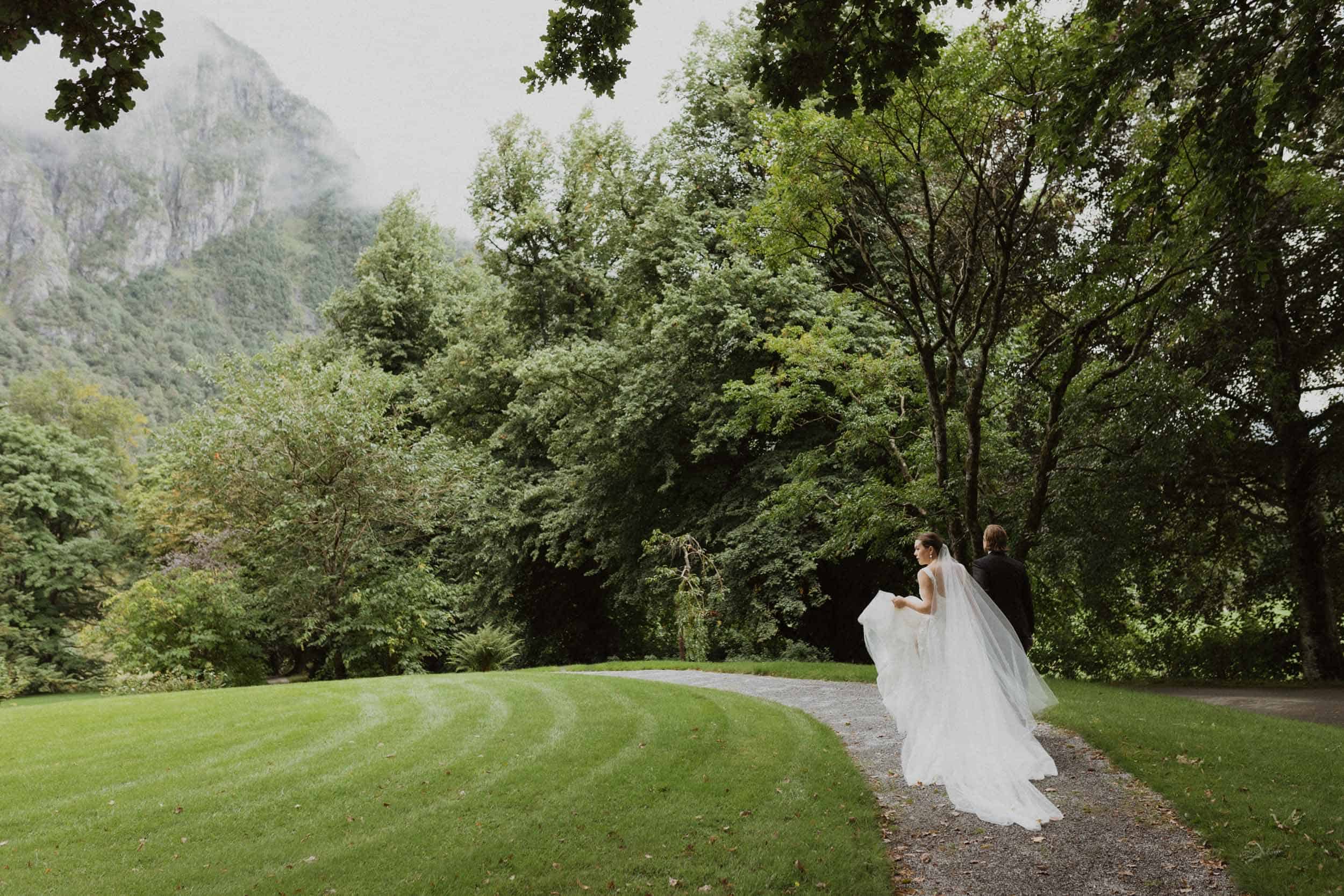 et brudepar på spasertur i en grønn park