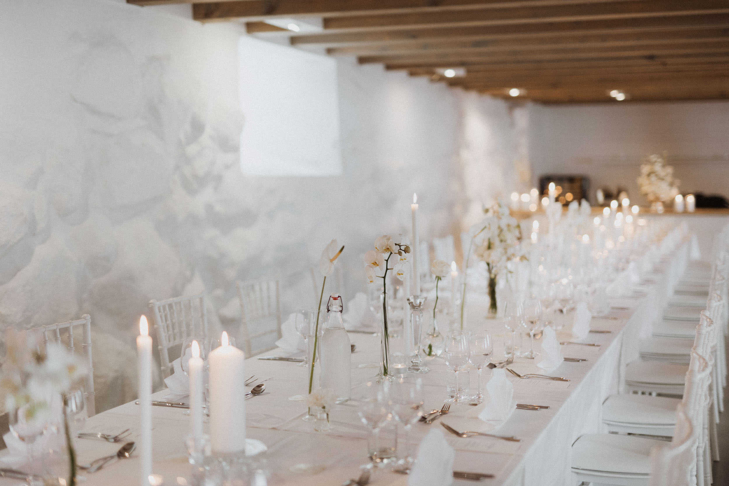 et lang bord med hvit borddekking og hvite stoler