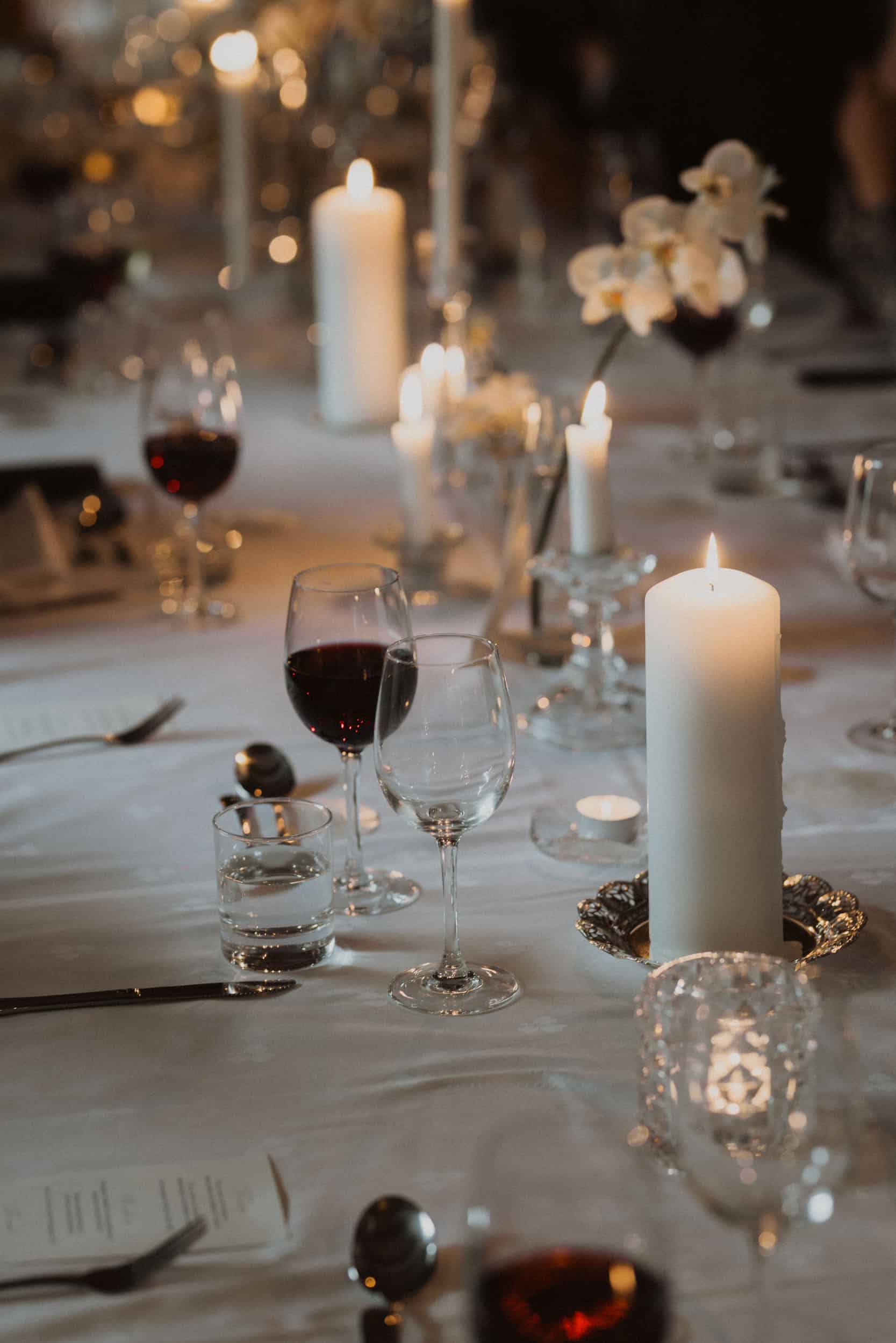 bord med stearinlys, bestikk og glass med vin