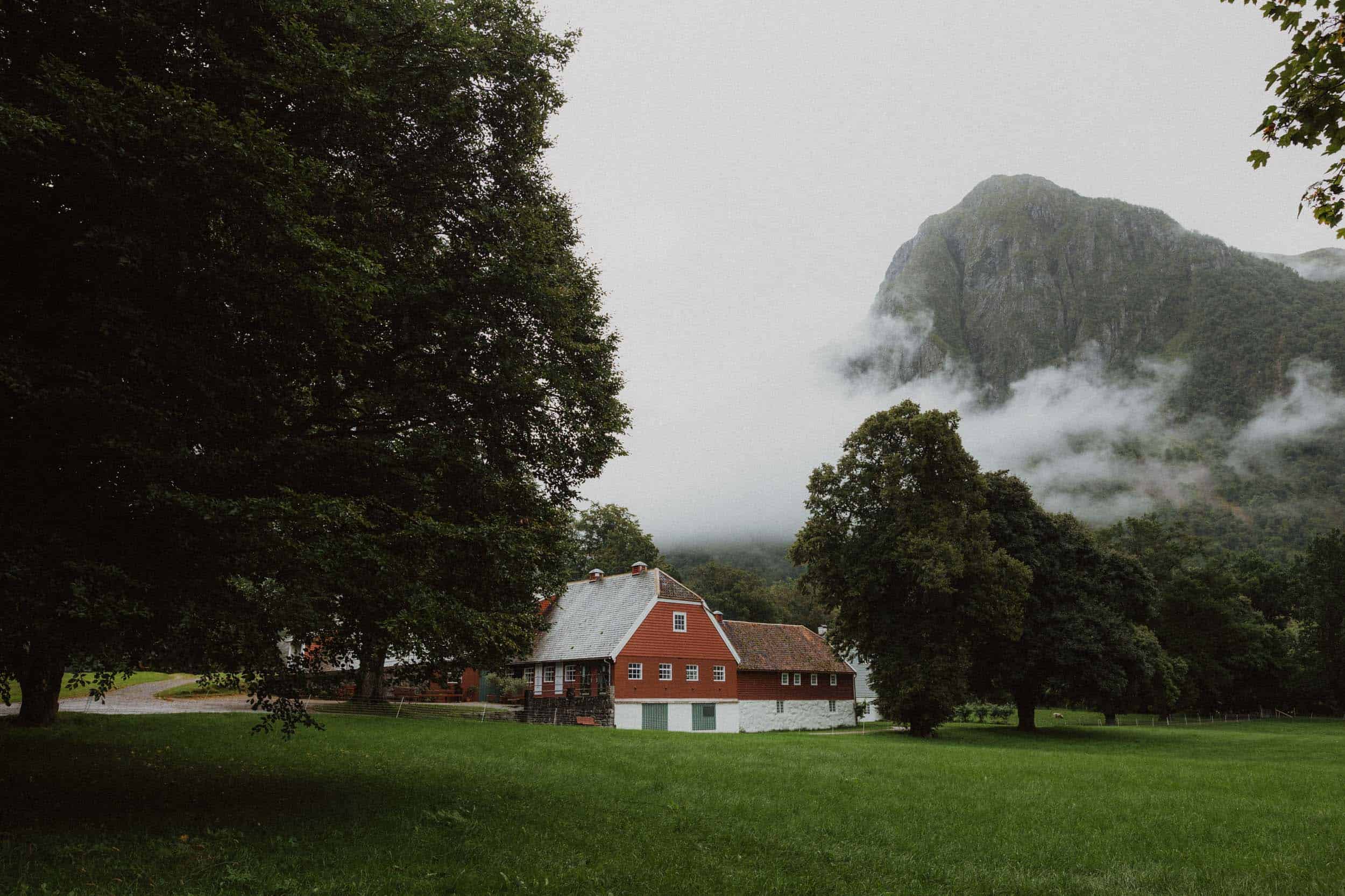 et rødt hus på enga blant store trær