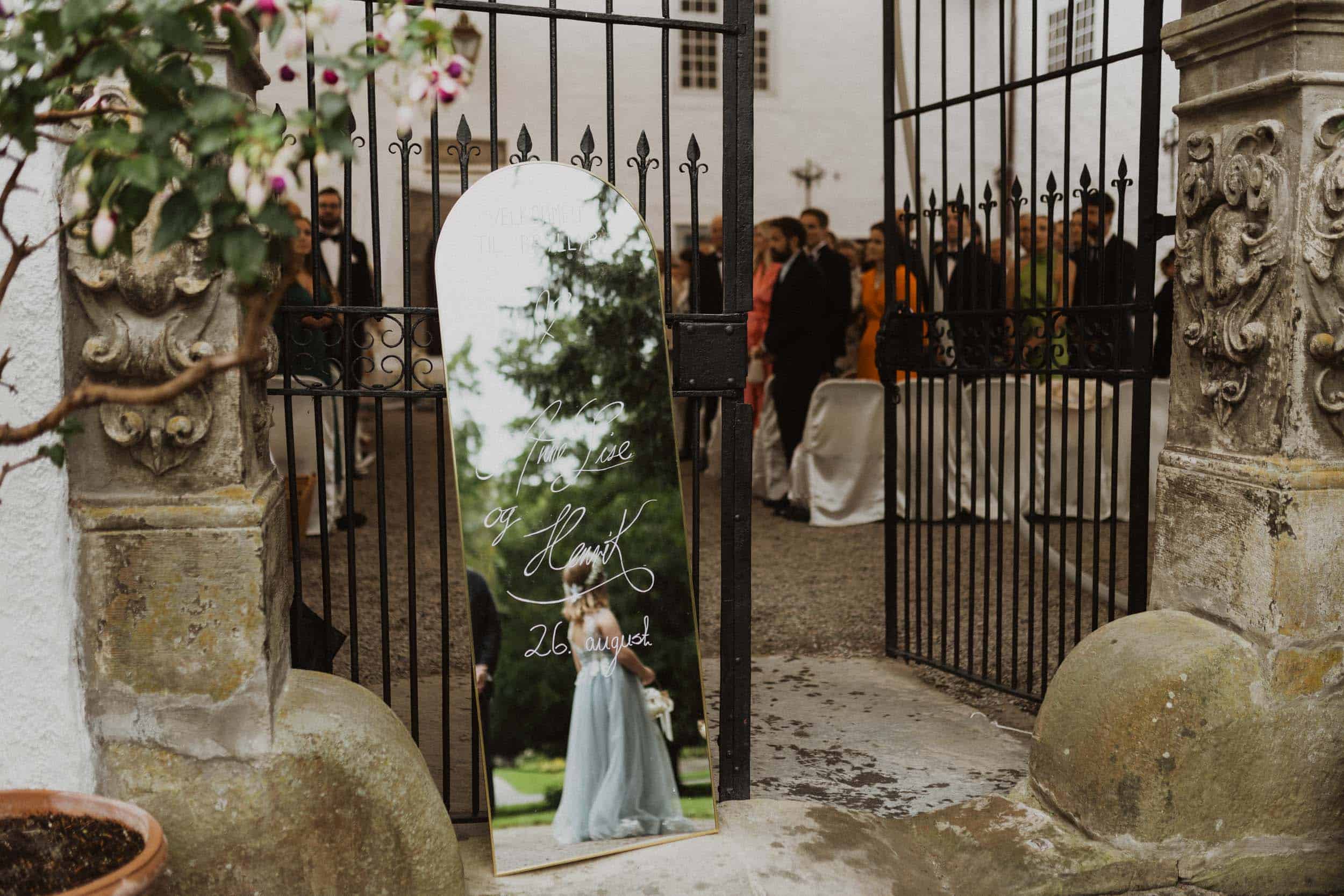 speil med refleksjon av en jente, en port med mennesker som står bak den