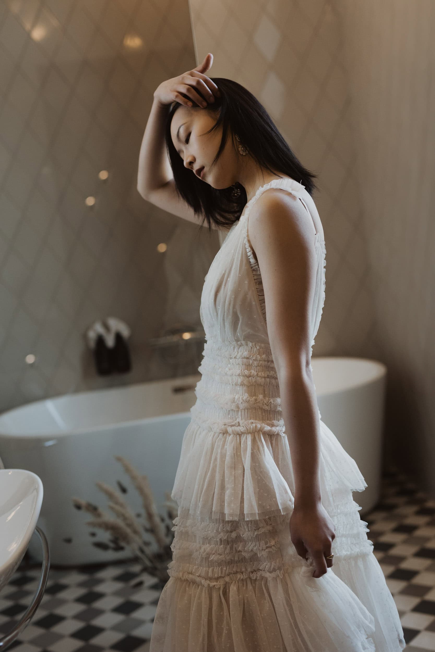 en kvinne med kort, svart hår i hvit kjole i en bad
