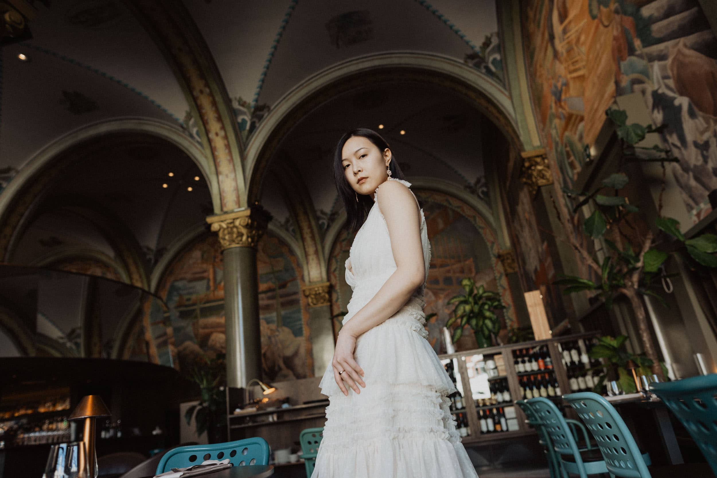 kvinne i hvit kjole som står i en stor sal