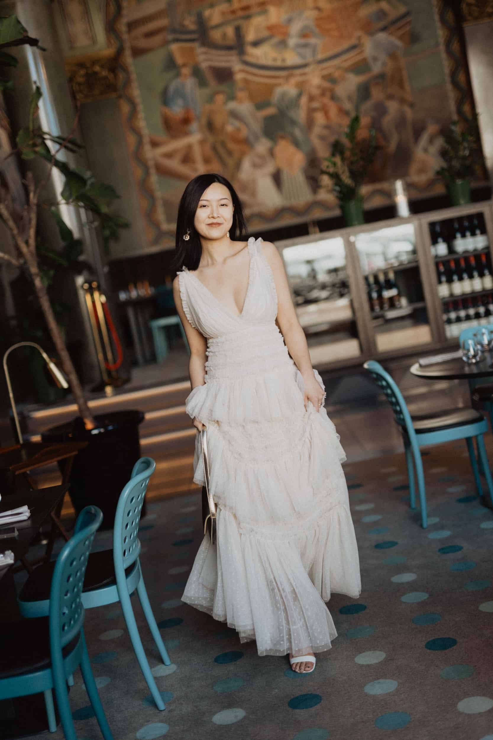 en kvinne i hvit kjole som går i en fargerik restaurant