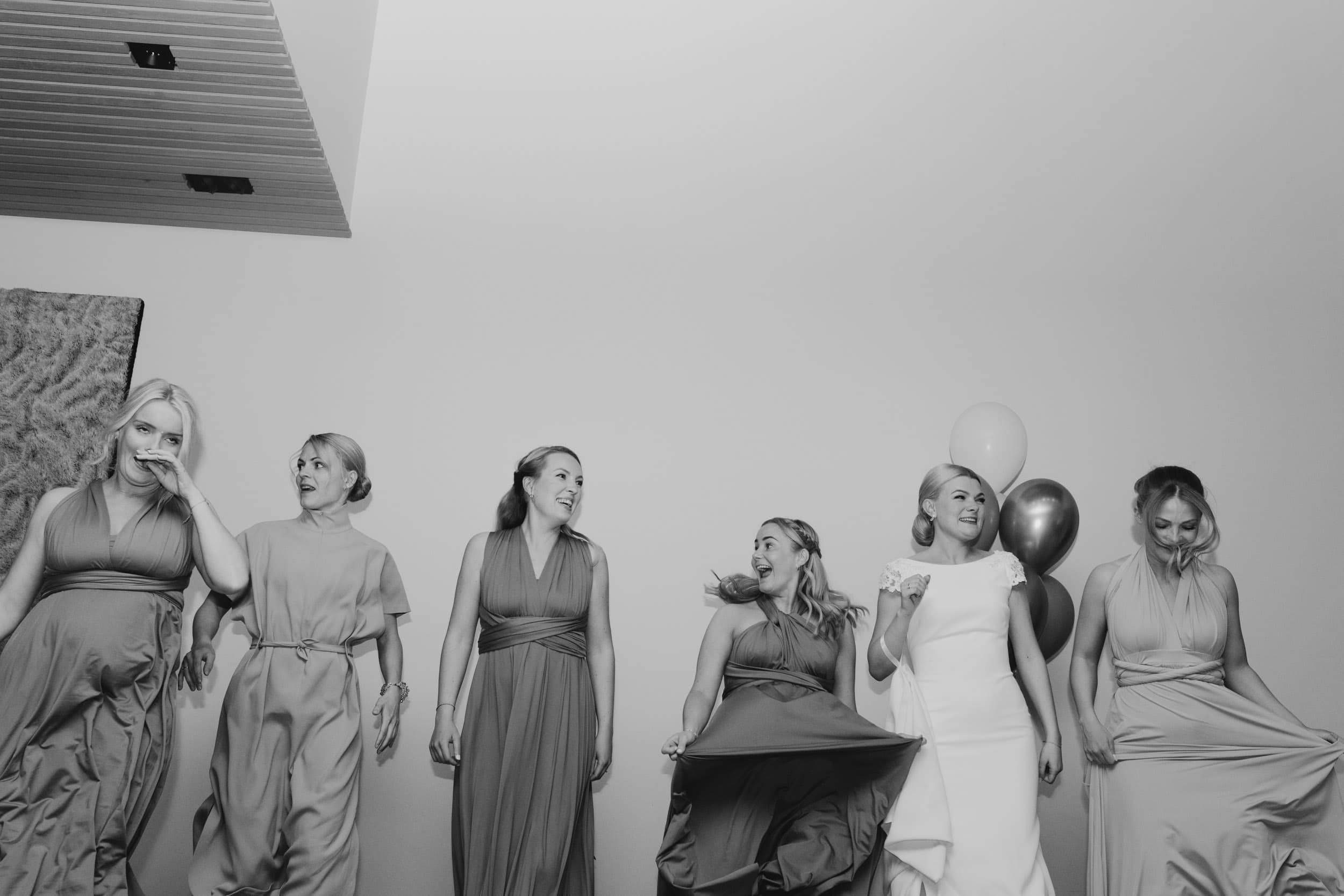 seks kvinner i fine kjoler som danser mot hvit vegg