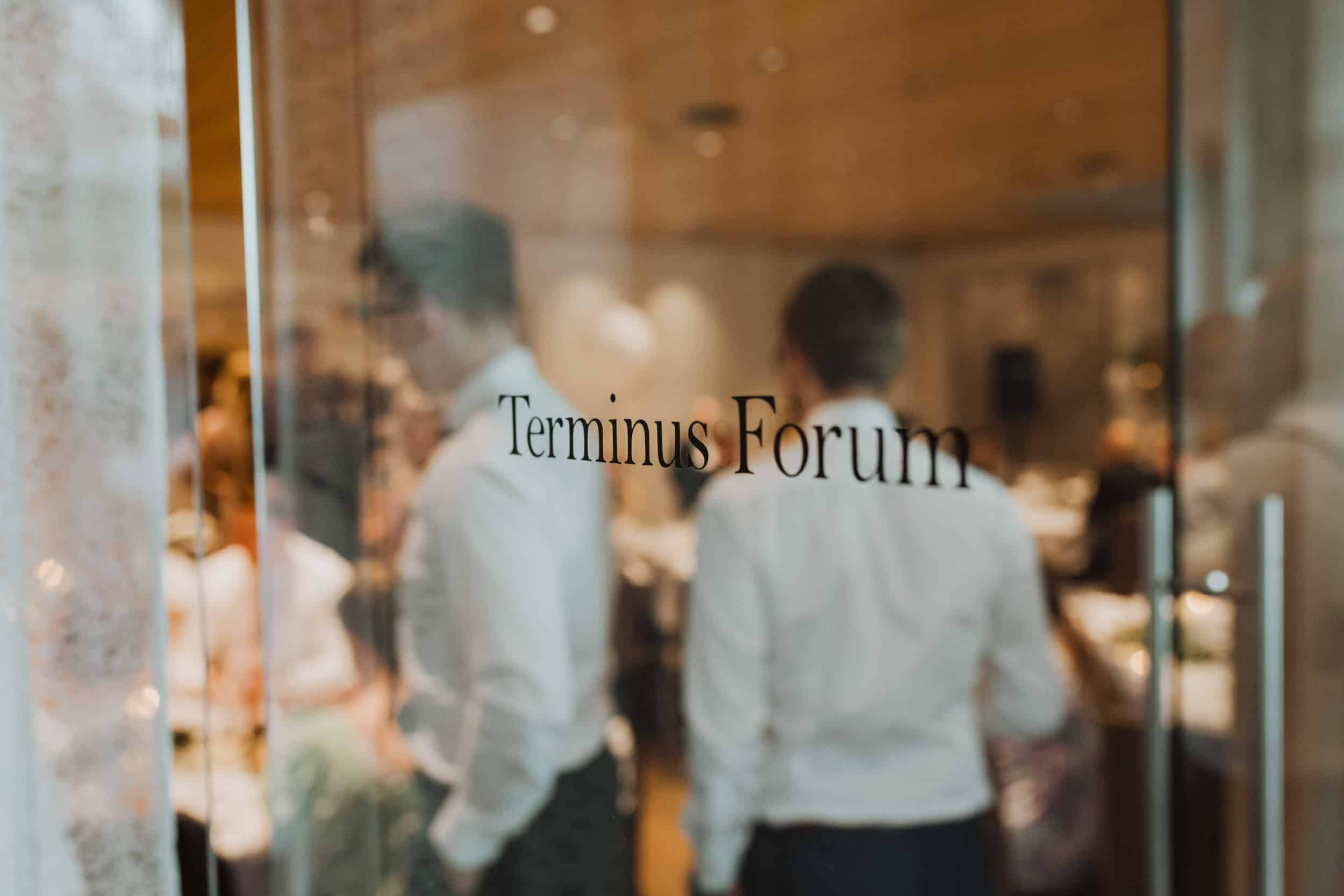 det står terminus forum på glassdøren og mennesker ut av fokus bak døren