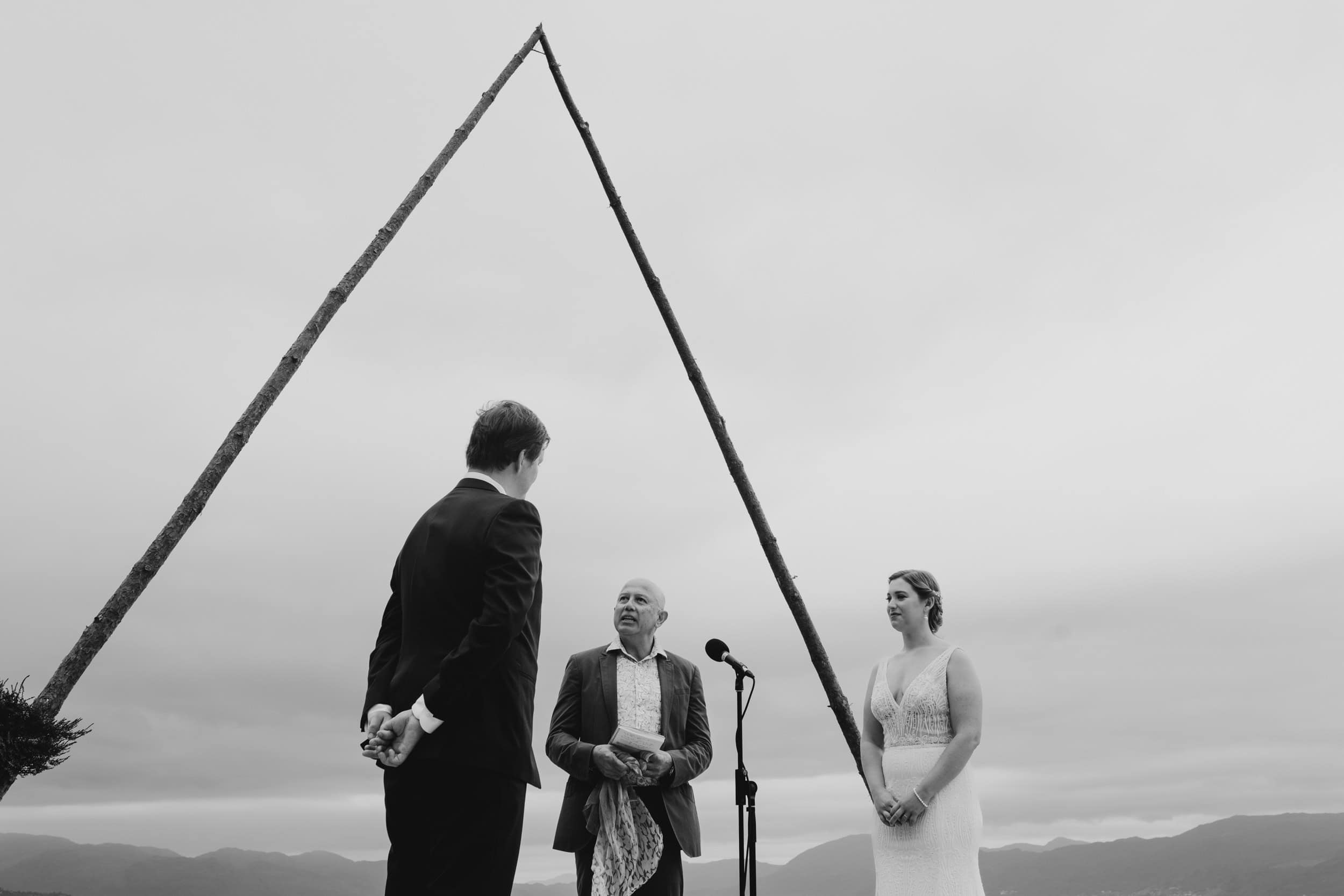 brudepar og en mann står under trekantet ting