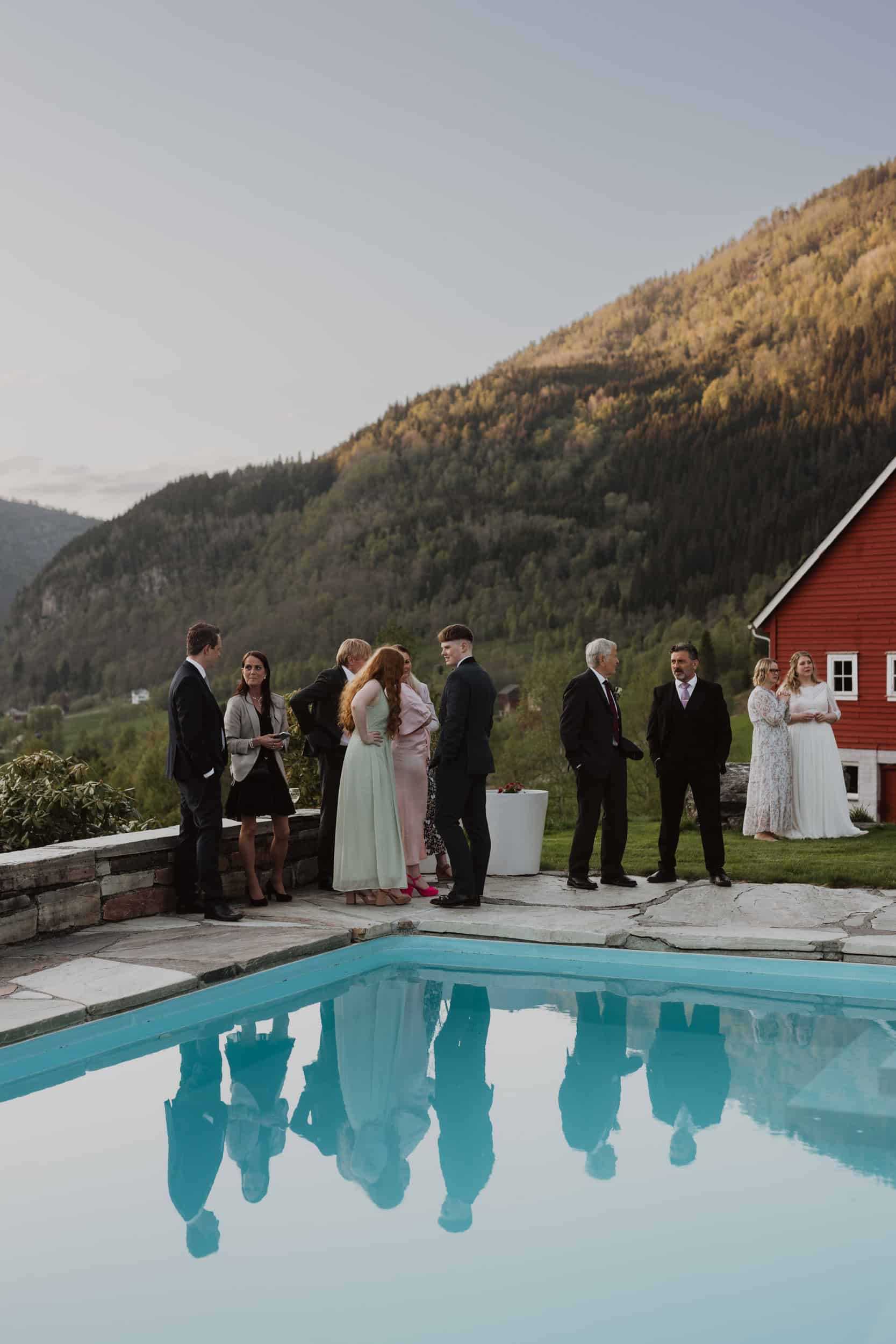 mennesker som står ved svømmebasseng og fjell bak dem