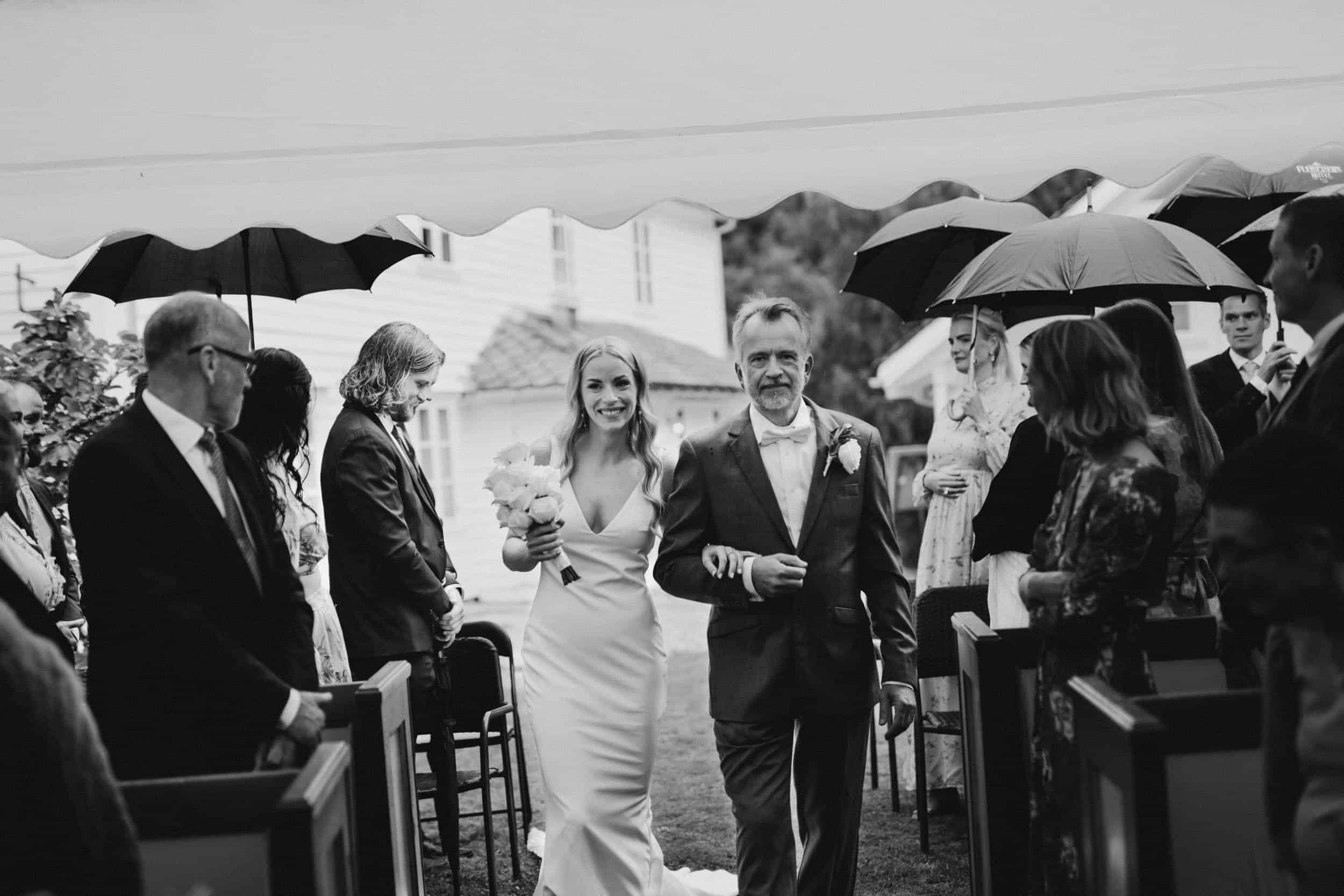 en mann som går med en brud blant mennesker som holder paraplyer