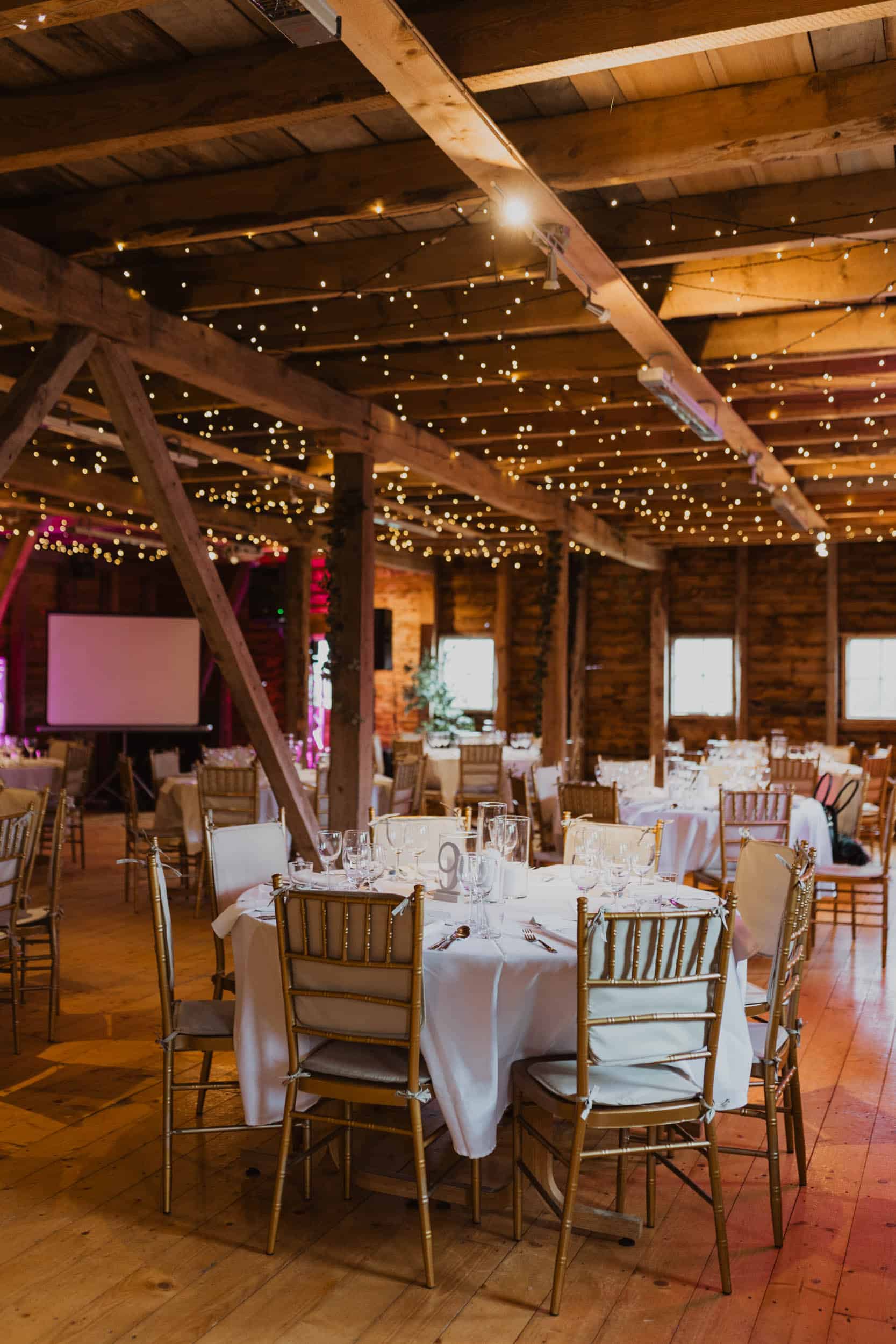 et pyntet lokale med tre vegg, runde bord med hvite dukk og gule stoler