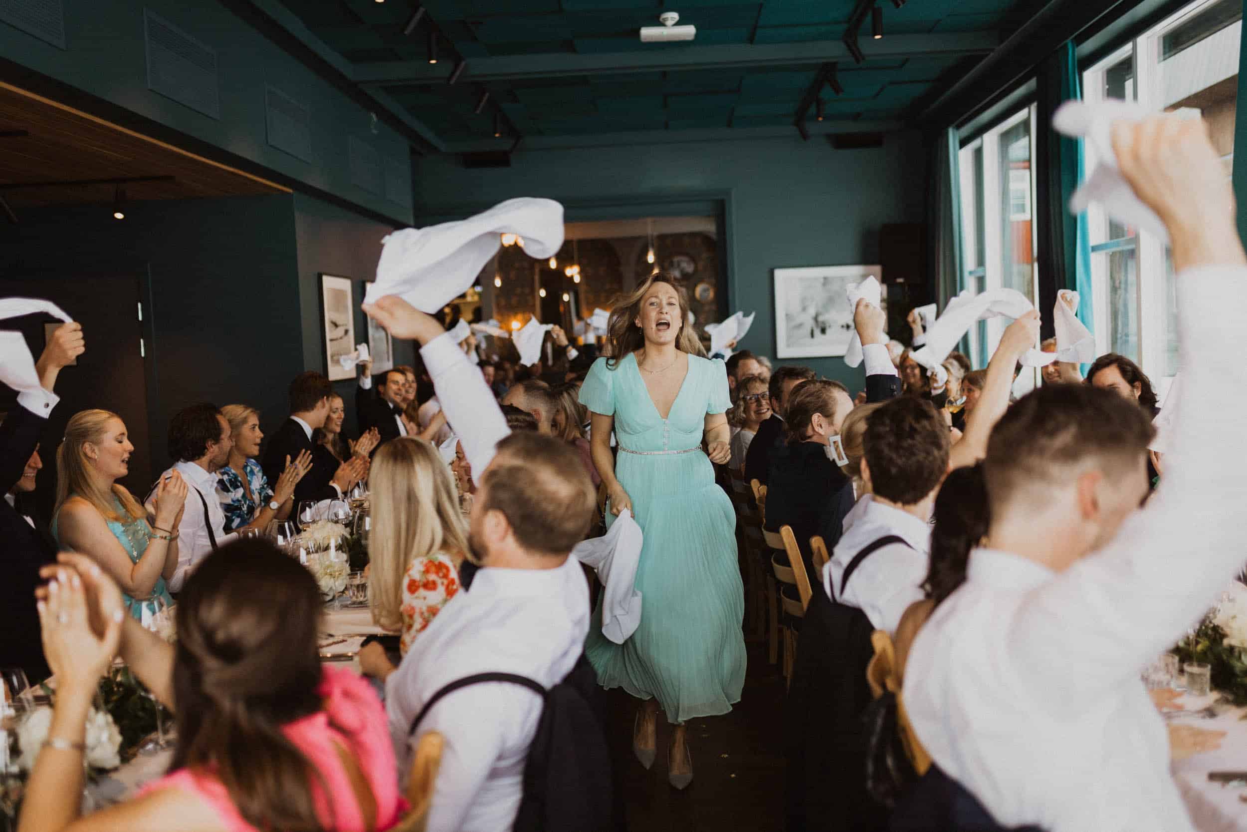 kvinne som løper og synger blant bordene, andre jubler