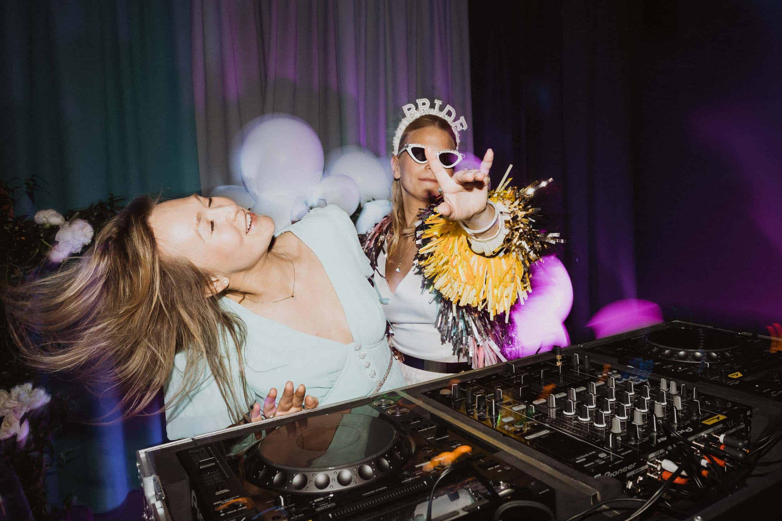 to kvinner bak DJ-station som danser og har det gøy