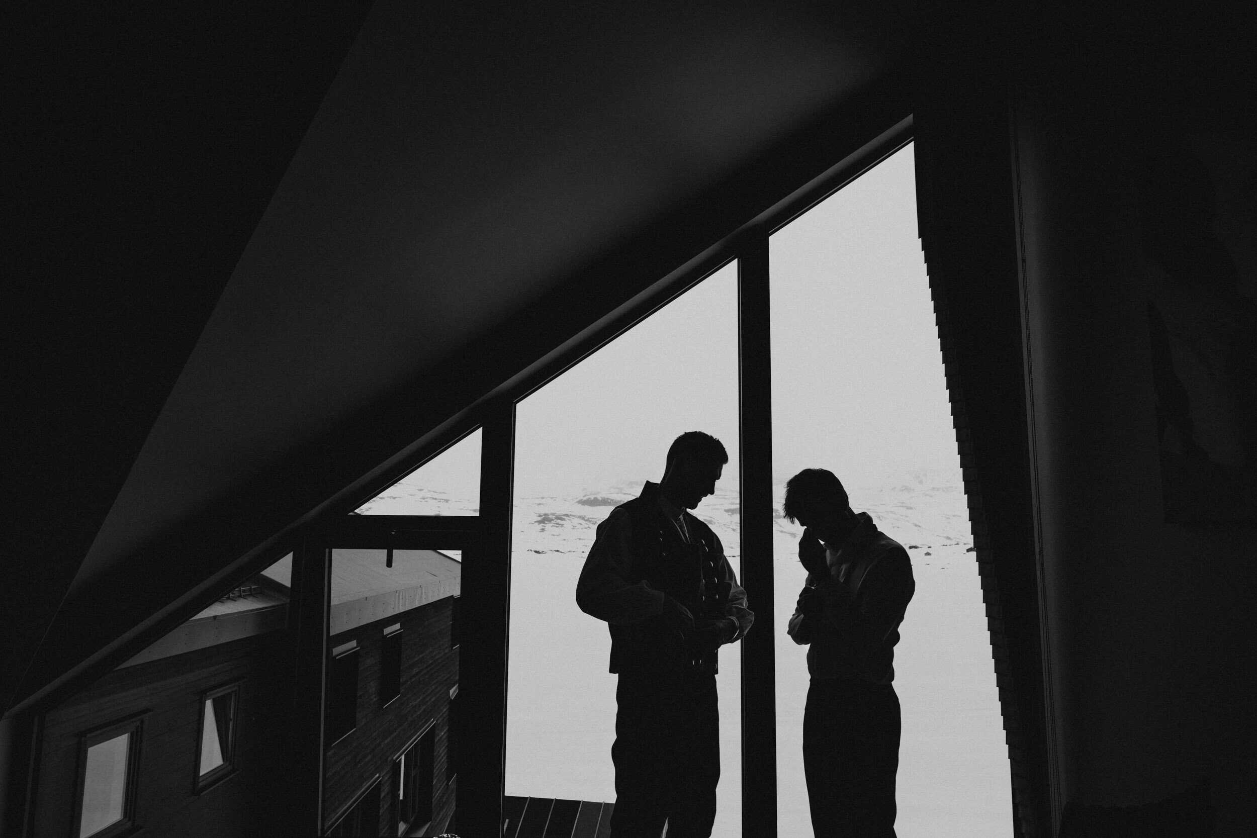 silhuetter av to men på et rom mot lys