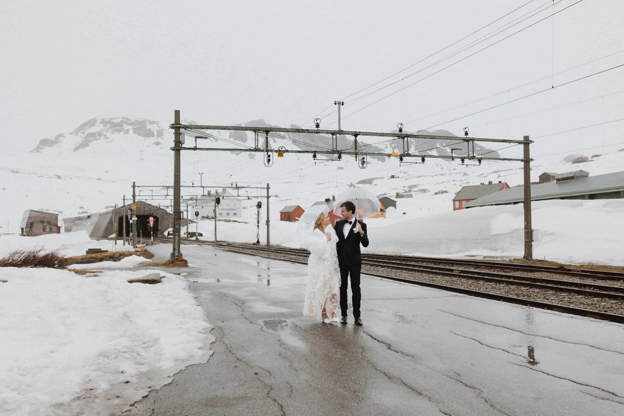 brudepar går på togstasjon, masse snø rundt dem