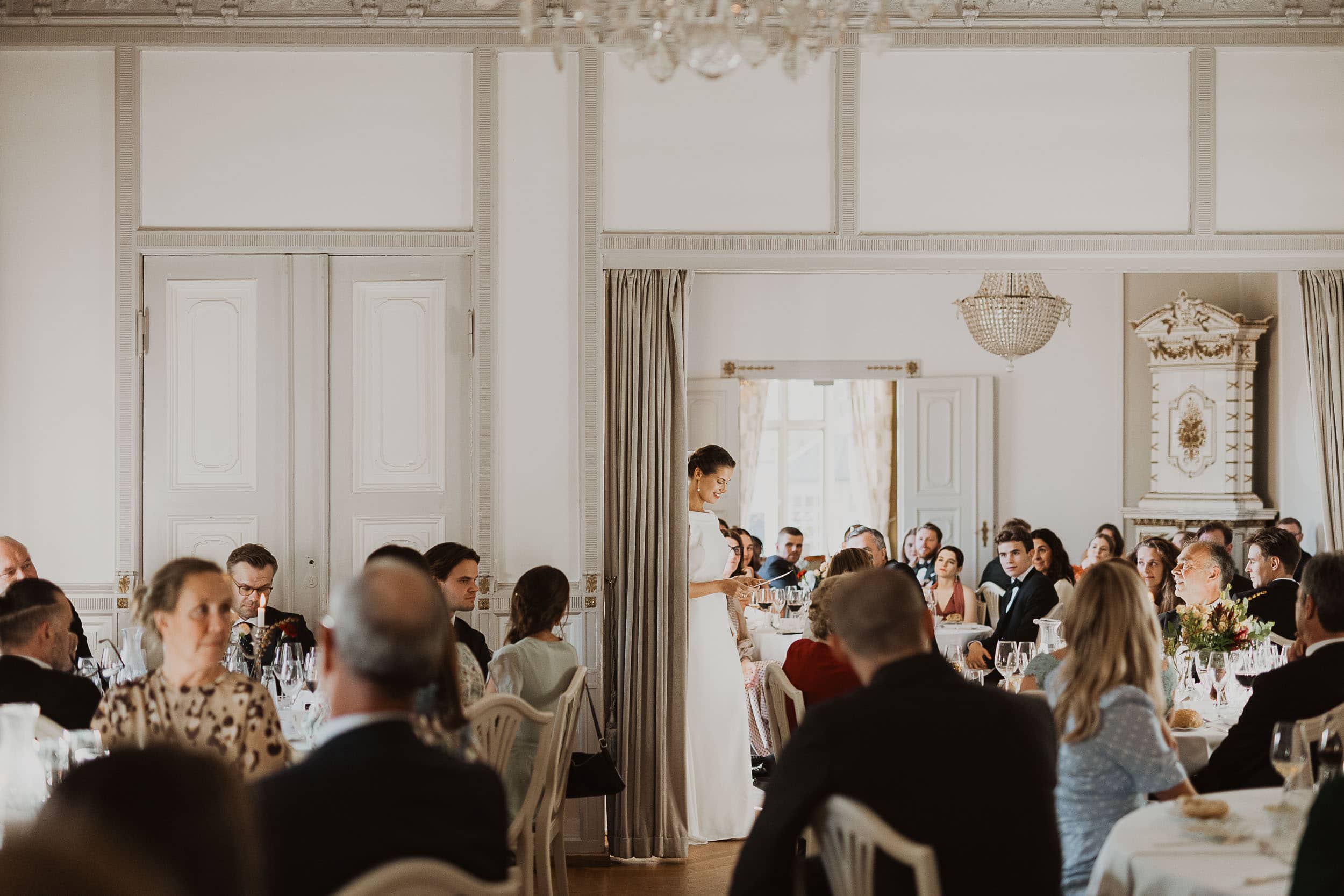 rom fult av folk med en brud i midten som leser noe