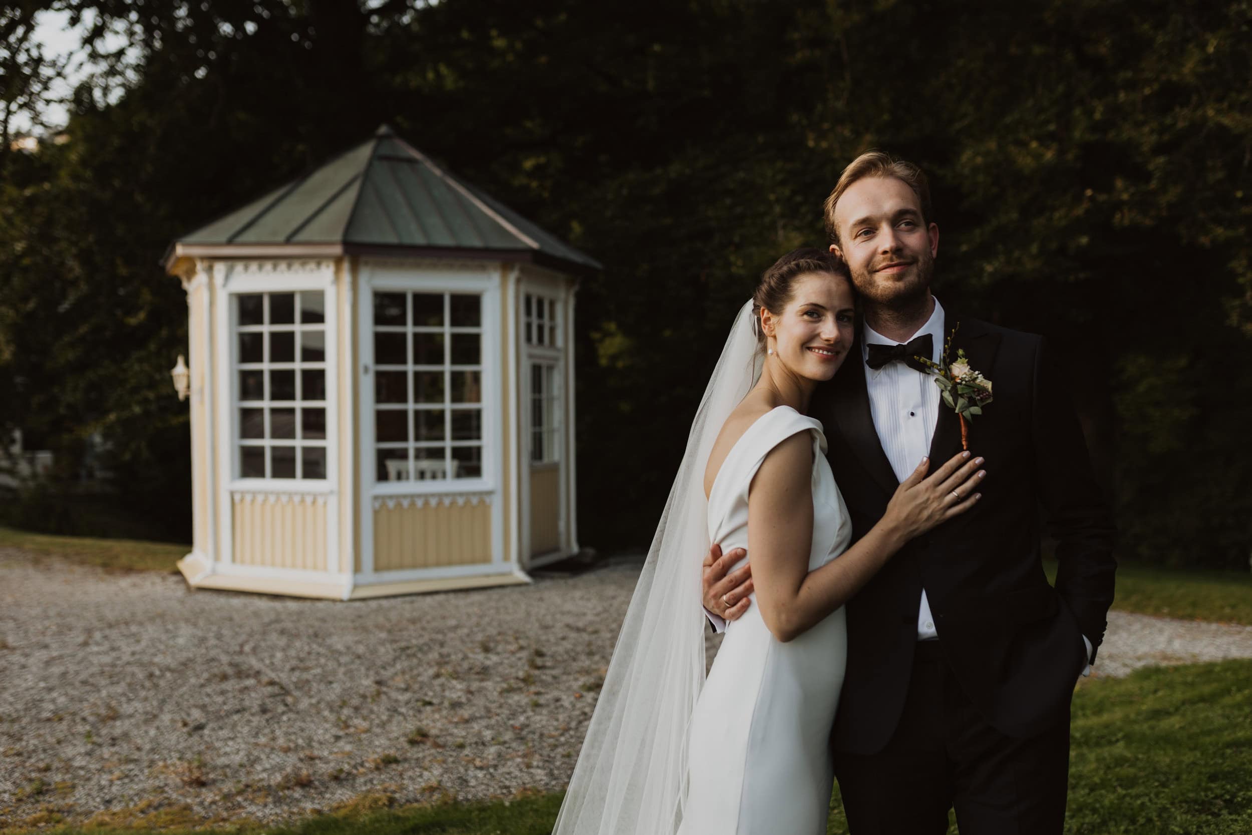 smilende brudepar med et hus bak dem