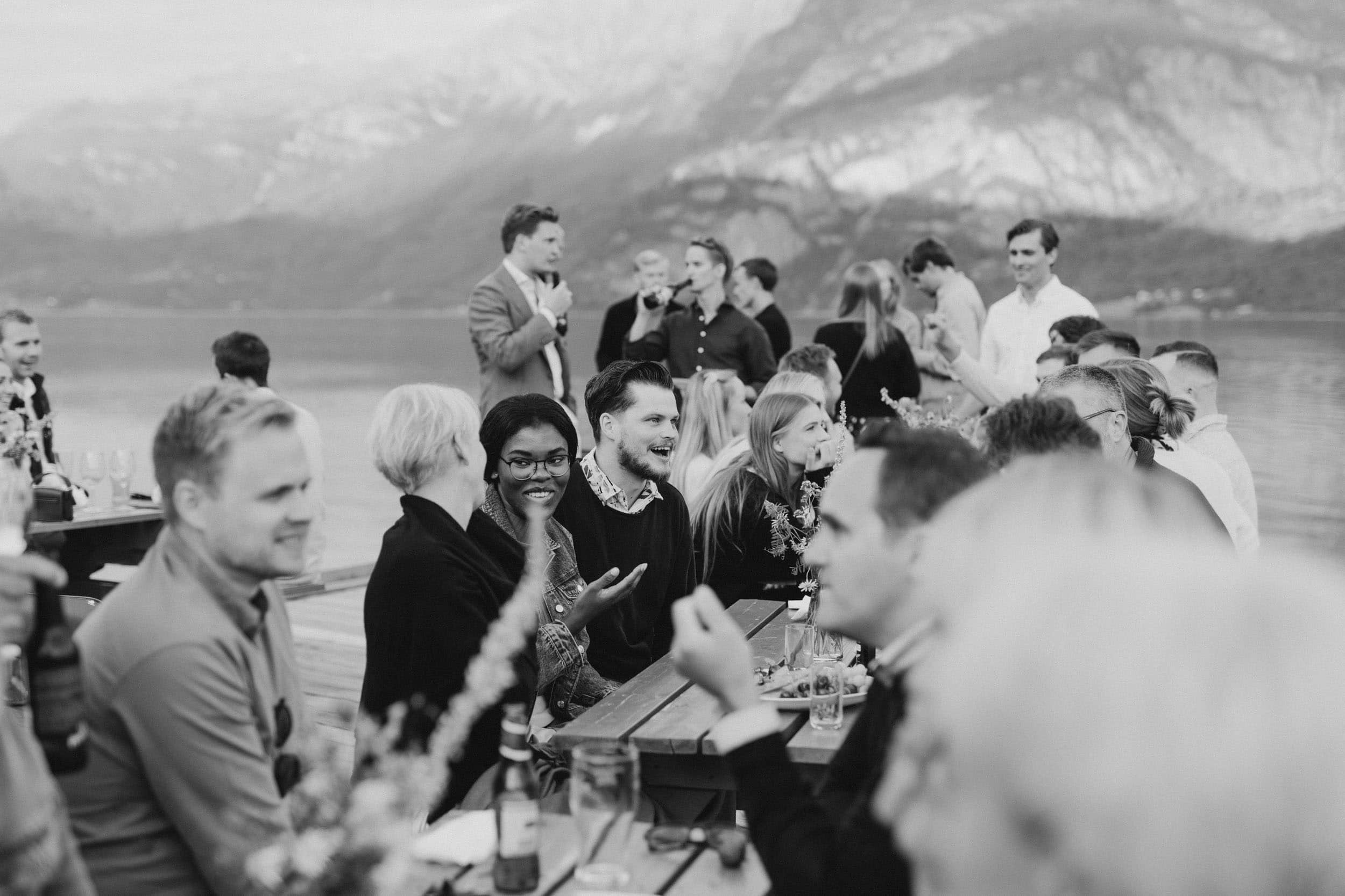 mennesker sitter ved et bord ute ved vannet og prater
