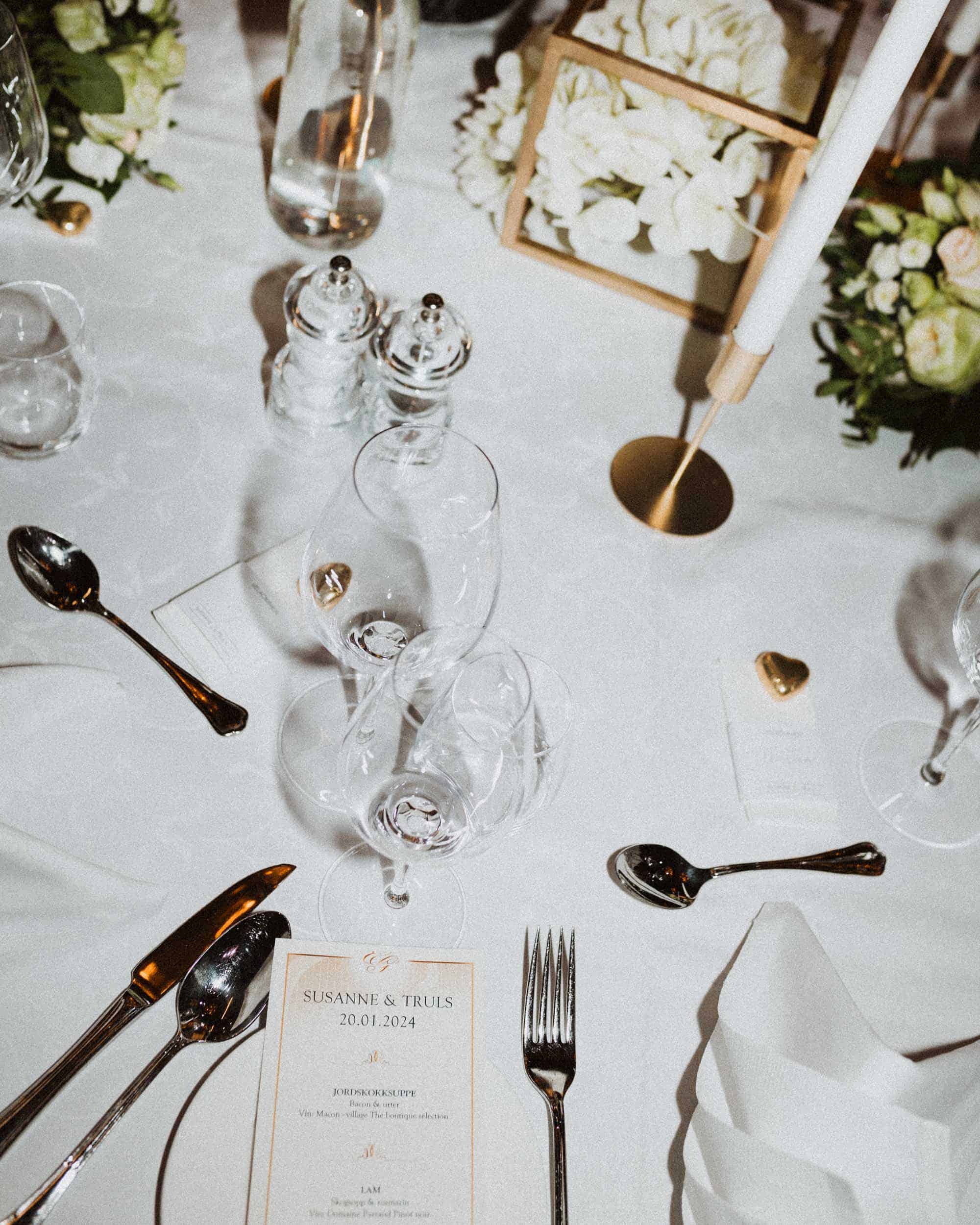 bord me bestikk, lysholder, vinglass og blomster