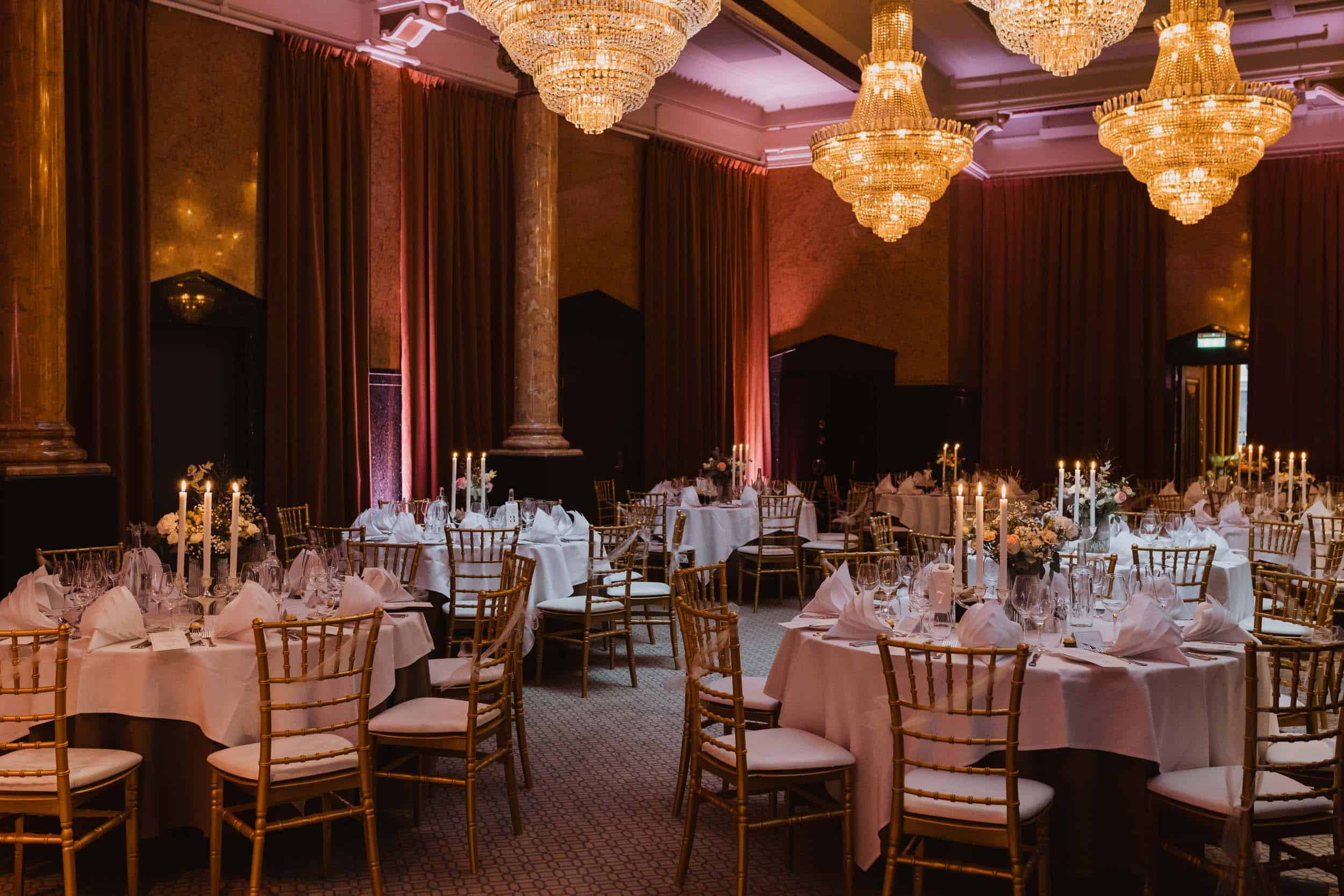 innside av et spisesal med runde bord, gulle stoler og rosa lys i lokale