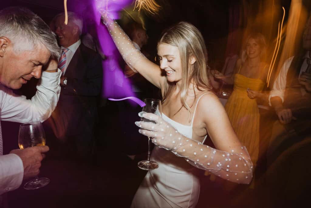 en kvinne danser i hvit kjole med et drikk i hånden