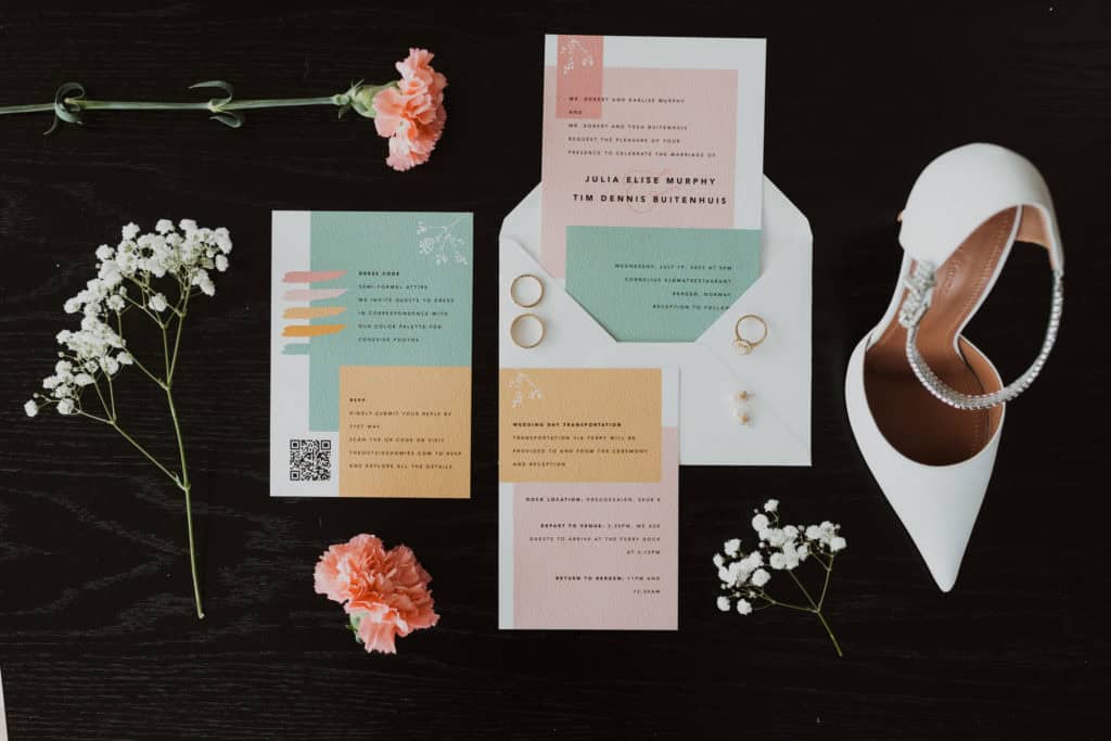 bryllupsinvitasjon, blomster, brudesko, og gifteringer på et svart bord